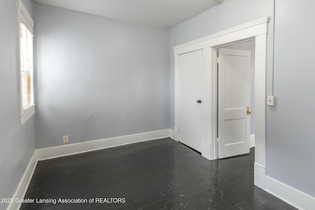 empty room featuring dark wood-type flooring and baseboards