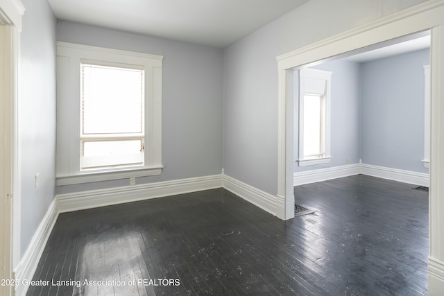 spare room with visible vents, baseboards, and hardwood / wood-style flooring