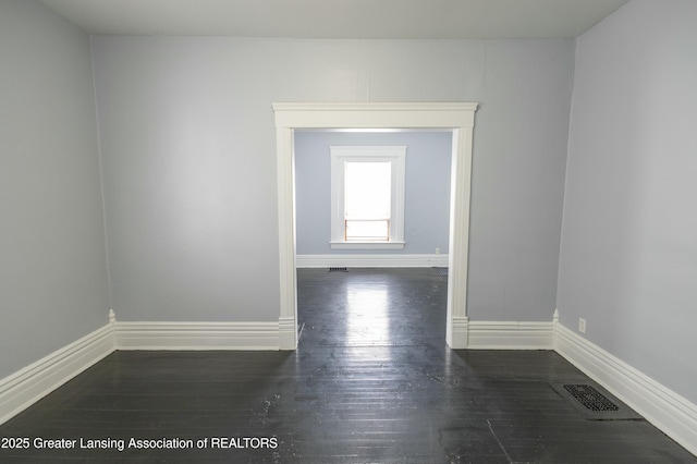 unfurnished room featuring visible vents, baseboards, and wood finished floors