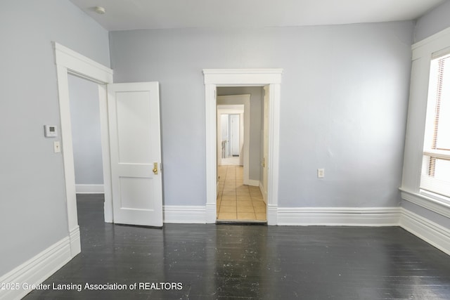 spare room featuring baseboards and wood finished floors