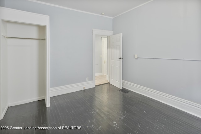 unfurnished bedroom featuring visible vents, crown molding, baseboards, and wood finished floors