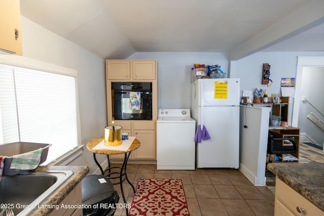 kitchen featuring washer / clothes dryer, freestanding refrigerator, oven, dark countertops, and dark tile patterned floors