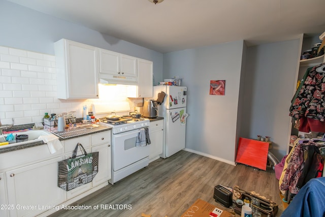 kitchen with under cabinet range hood, wood finished floors, white cabinetry, white appliances, and decorative backsplash