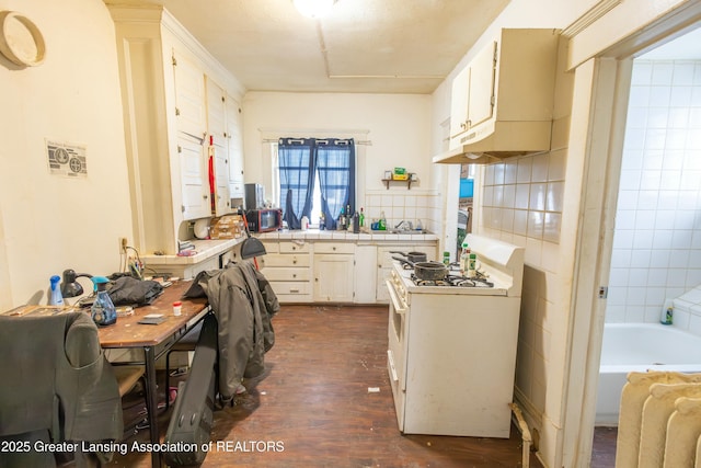 kitchen featuring gas range gas stove, tile counters, dark wood-style flooring, white cabinets, and a sink