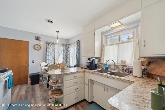 kitchen with white range with electric stovetop, visible vents, light countertops, and a sink