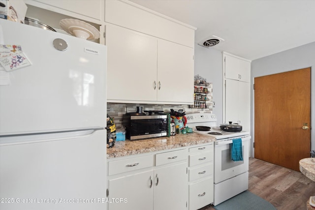 kitchen featuring white appliances, wood finished floors, visible vents, light countertops, and tasteful backsplash