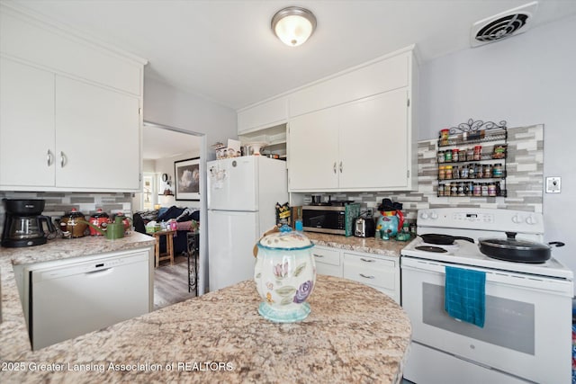 kitchen with white appliances, tasteful backsplash, visible vents, light stone countertops, and white cabinetry