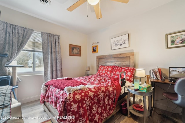 bedroom featuring a ceiling fan, wood finished floors, visible vents, and baseboards