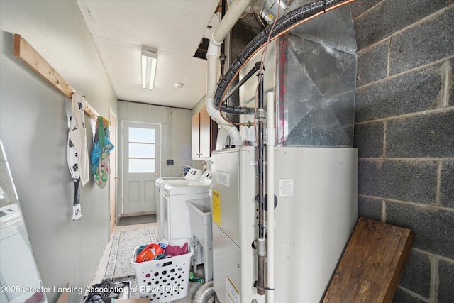 laundry area with concrete block wall, cabinet space, and separate washer and dryer