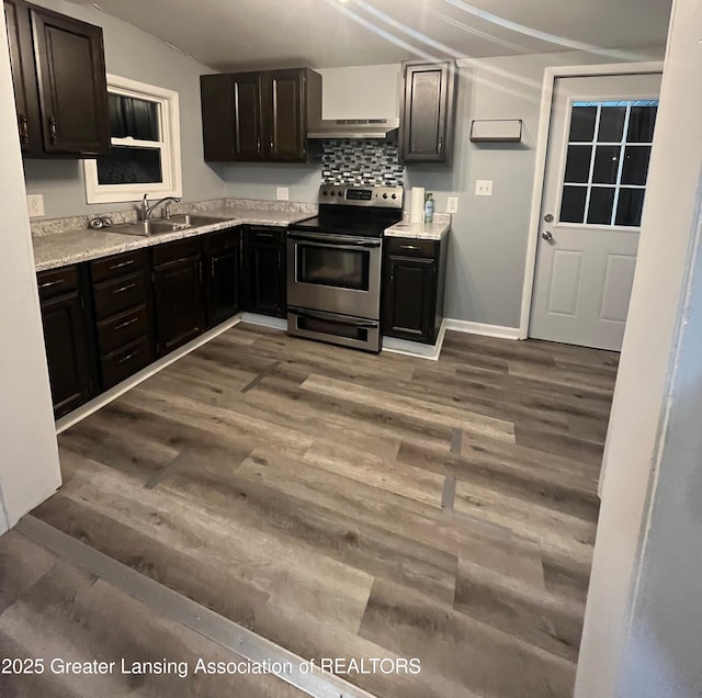 kitchen with a sink, under cabinet range hood, wood finished floors, light countertops, and stainless steel electric range oven