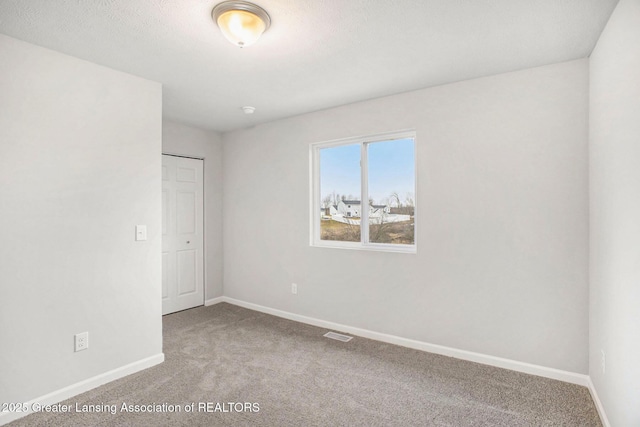 carpeted empty room featuring visible vents and baseboards