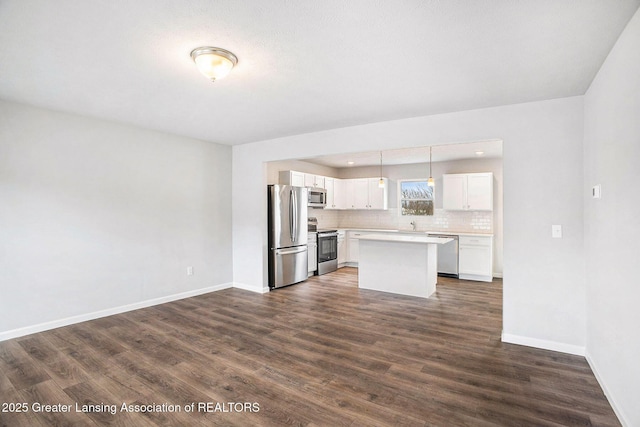 kitchen with stainless steel appliances, white cabinetry, light countertops, backsplash, and dark wood finished floors