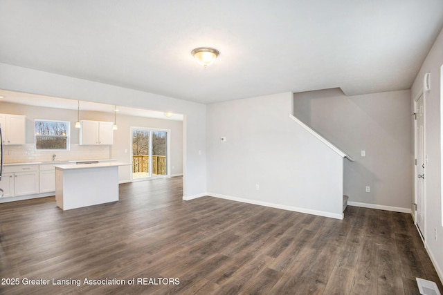 unfurnished living room featuring a sink, dark wood finished floors, visible vents, and baseboards