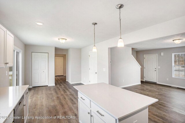 kitchen featuring dark wood-type flooring, a kitchen island, white cabinetry, baseboards, and light countertops