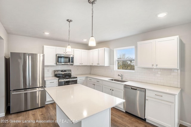 kitchen with white cabinets, dark wood finished floors, stainless steel appliances, and a sink