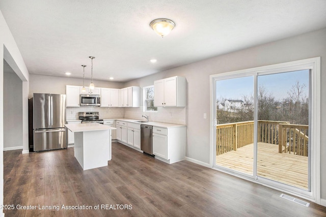 kitchen with dark wood-type flooring, a sink, visible vents, appliances with stainless steel finishes, and backsplash