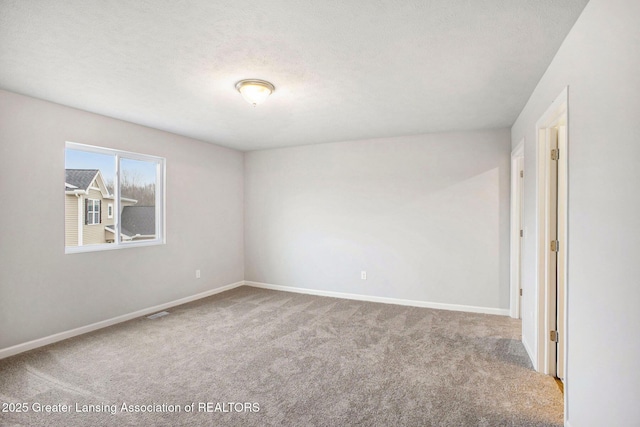 spare room with carpet, visible vents, a textured ceiling, and baseboards