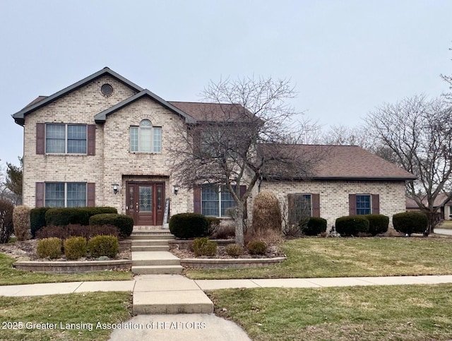 traditional-style home featuring roof with shingles, a front yard, and brick siding