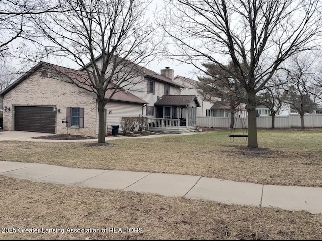 view of front facade featuring brick siding, concrete driveway, an attached garage, fence, and a front lawn