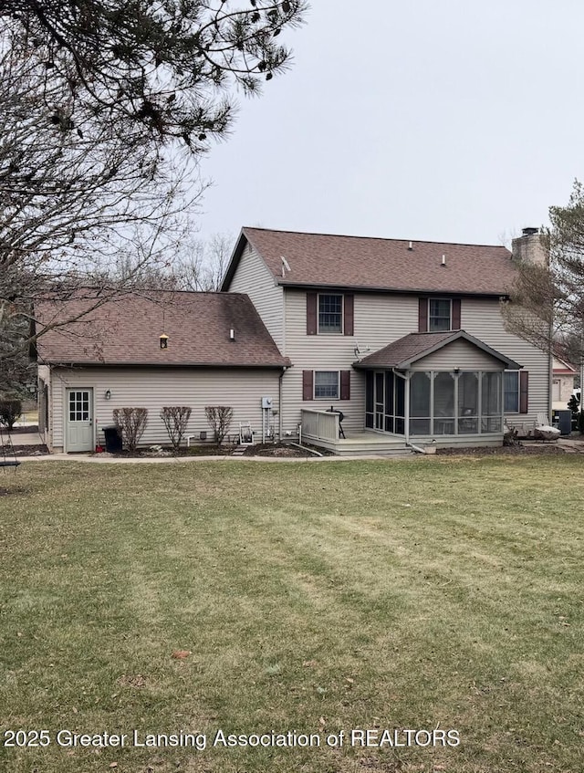 rear view of house featuring a sunroom, a chimney, and a lawn