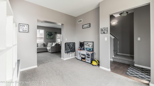 corridor with carpet floors, visible vents, and baseboards