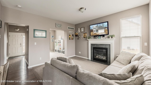 living area featuring a tile fireplace, visible vents, and baseboards