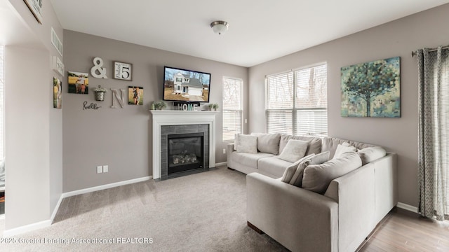 living area featuring visible vents, a fireplace, baseboards, and light colored carpet