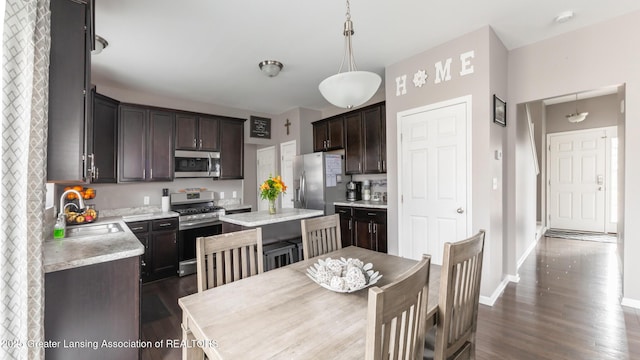 kitchen with dark brown cabinets, stainless steel appliances, a sink, and light countertops