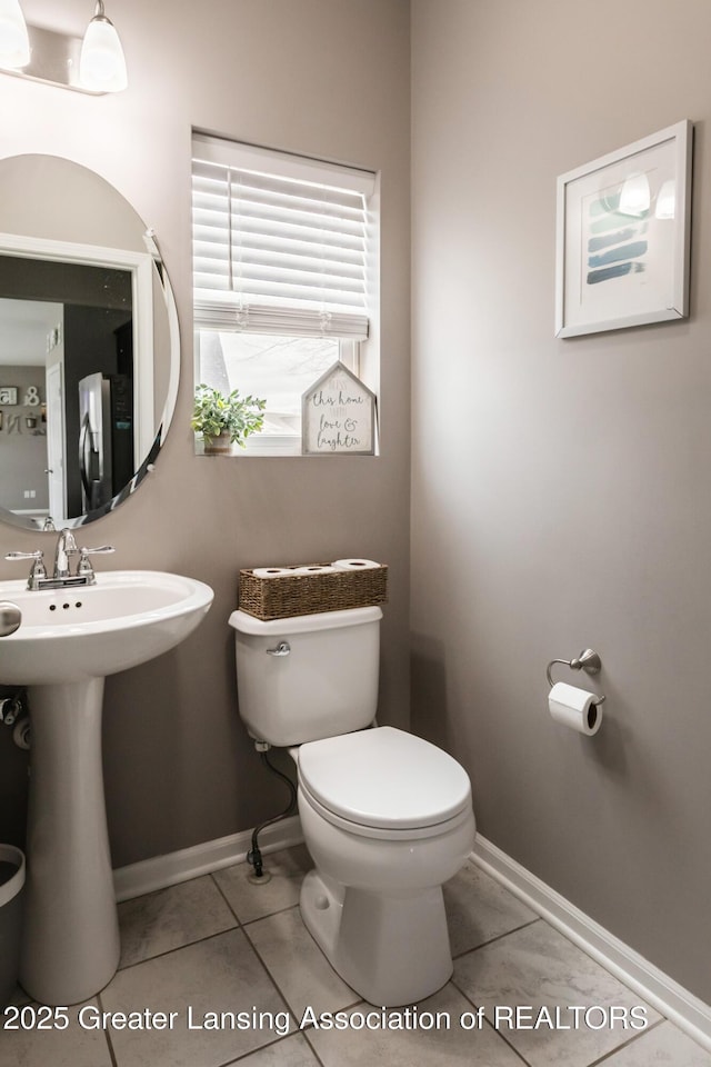 half bathroom with tile patterned flooring, toilet, and baseboards