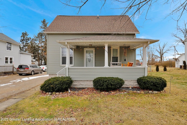 view of front of home with a porch, a shingled roof, and a front lawn