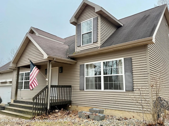 new england style home with a garage and roof with shingles