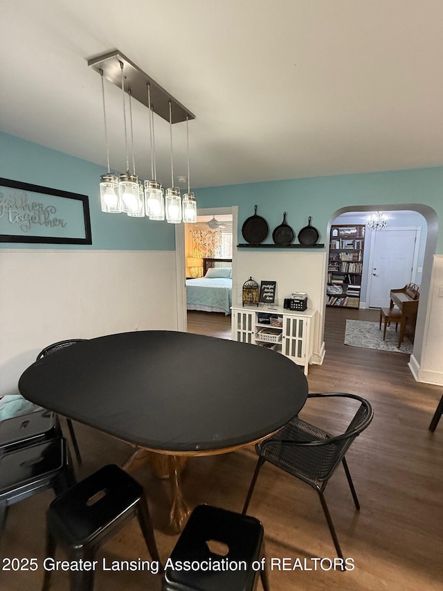 dining area with arched walkways and wood finished floors