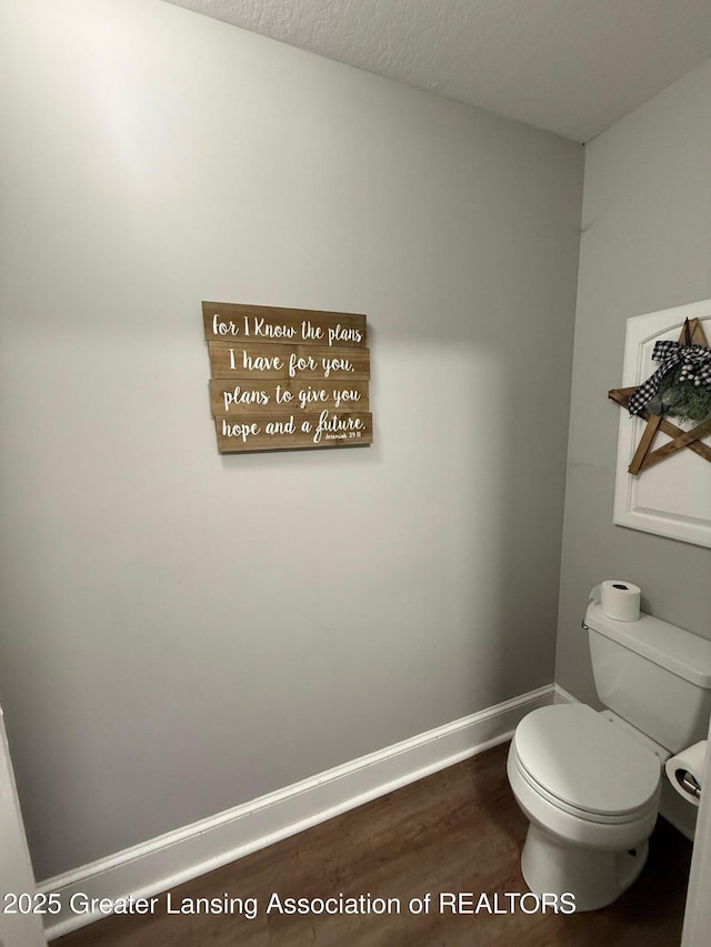 bathroom featuring toilet, a textured ceiling, baseboards, and wood finished floors