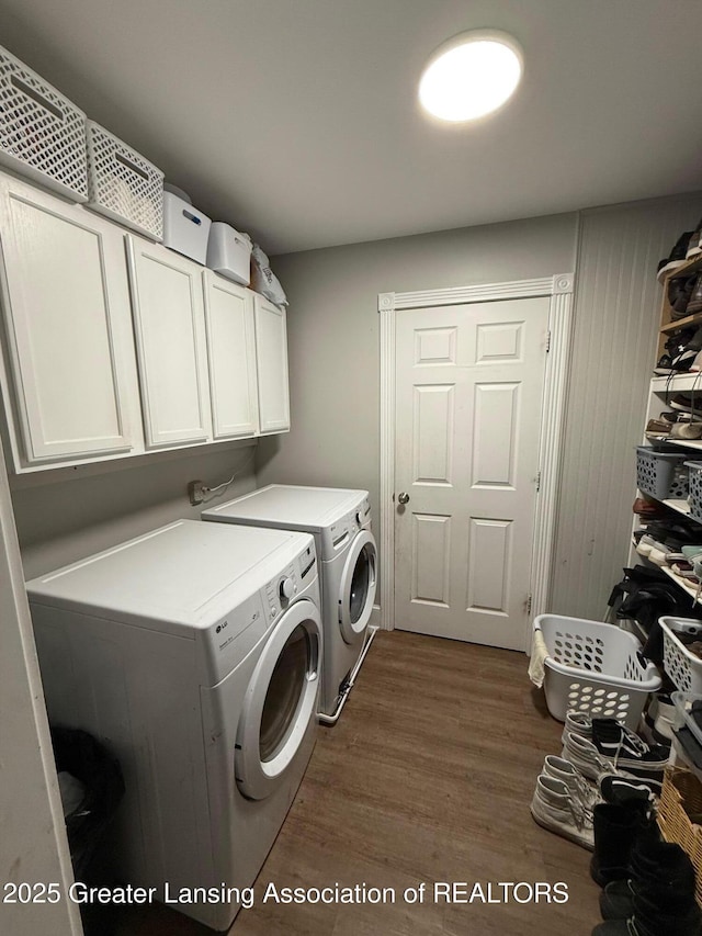 clothes washing area featuring cabinet space, washing machine and dryer, and dark wood-style floors