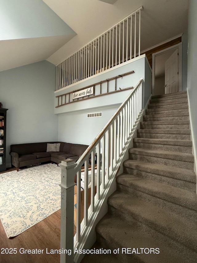 stairway featuring visible vents, vaulted ceiling, and wood finished floors