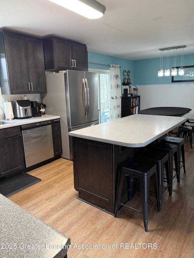 kitchen featuring light wood-style floors, a breakfast bar area, stainless steel appliances, and light countertops