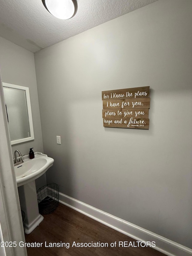 bathroom featuring baseboards, a textured ceiling, and wood finished floors