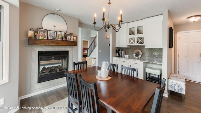 dining area featuring dark wood-style floors, a multi sided fireplace, stairs, and baseboards