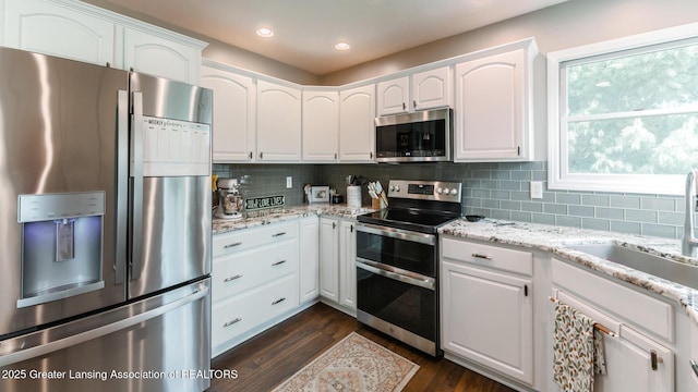 kitchen with appliances with stainless steel finishes, white cabinetry, a sink, and tasteful backsplash