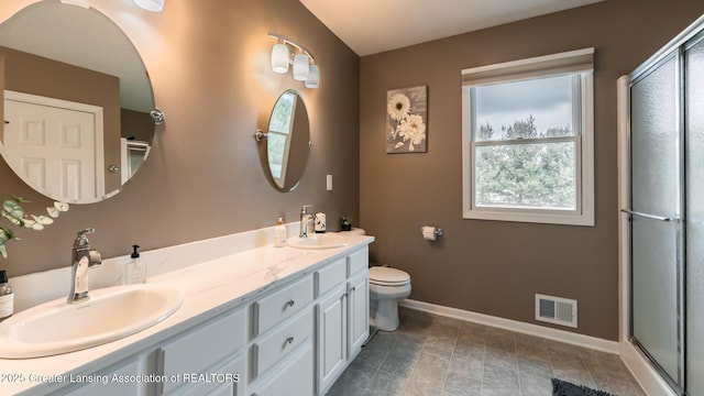 full bath with a shower with shower door, a sink, visible vents, and baseboards