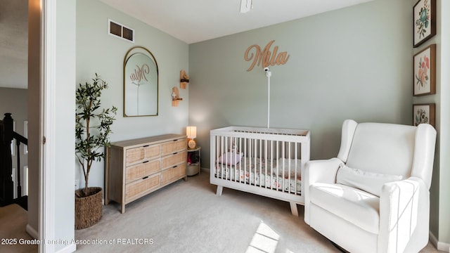 bedroom with a crib, carpet, and visible vents