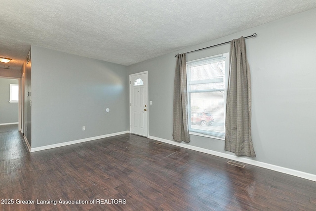 entrance foyer with visible vents, baseboards, dark wood-type flooring, and a textured ceiling