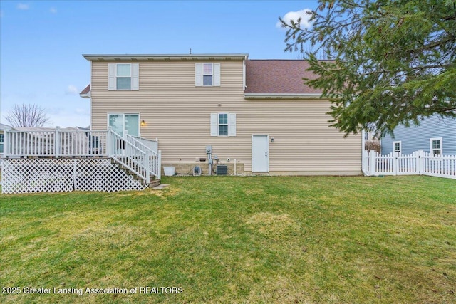 back of house with a deck, a lawn, and fence