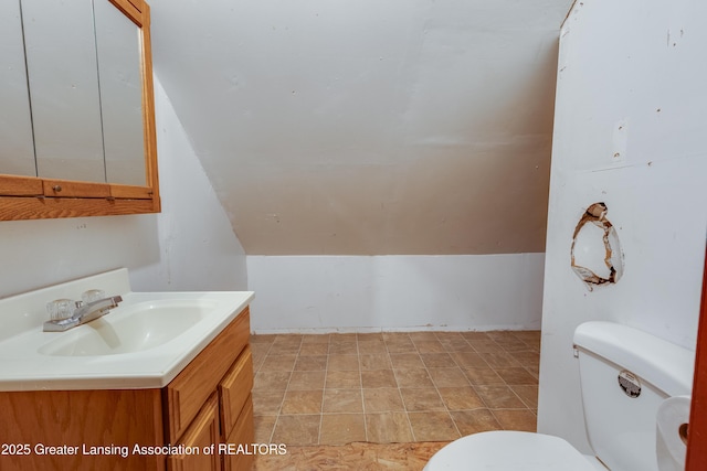 bathroom featuring toilet, lofted ceiling, and vanity