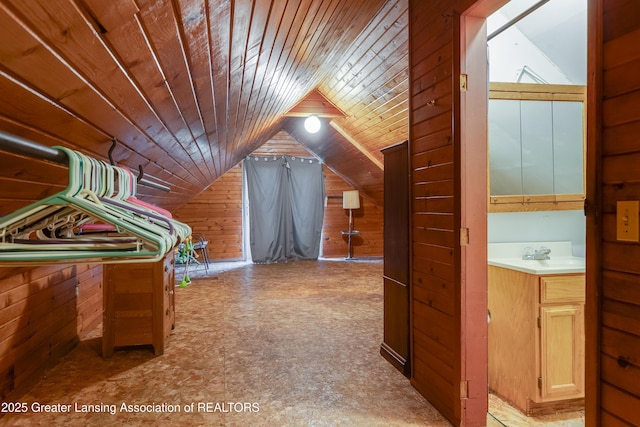 additional living space featuring wooden ceiling, vaulted ceiling, wooden walls, and a sink