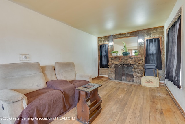 living area featuring a stone fireplace and hardwood / wood-style floors