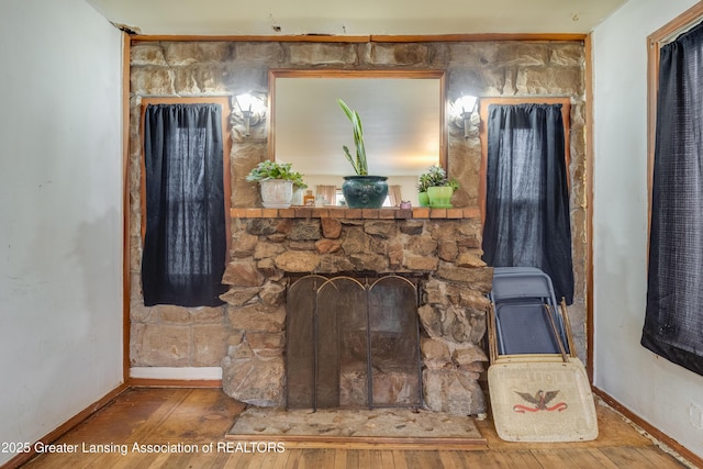 details with a stone fireplace, baseboards, and wood finished floors