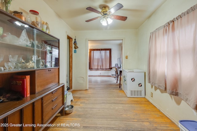 corridor featuring light wood-style flooring and baseboards