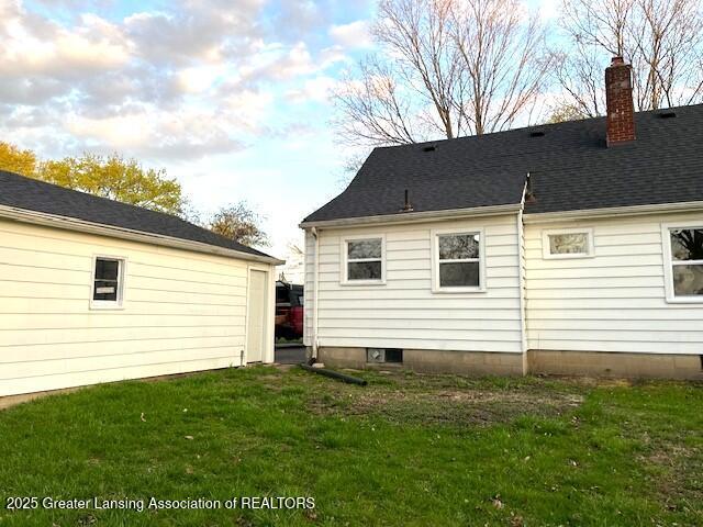 rear view of house featuring a lawn and a chimney
