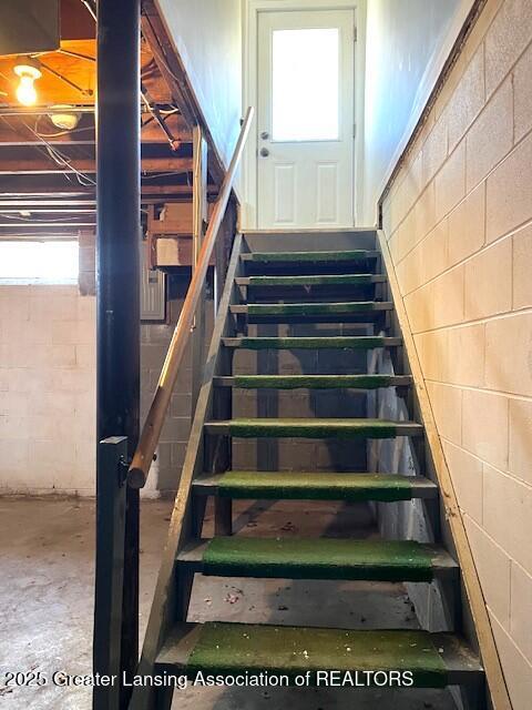 stairway featuring concrete block wall